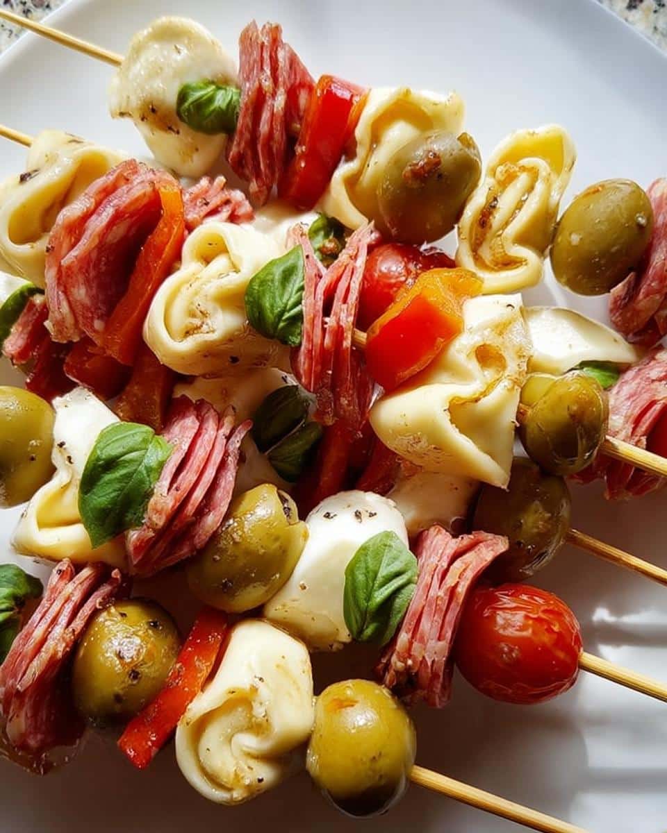 Close-up of Antipasto Skewers featuring tortellini, salami, mozzarella balls, olives, and basil leaves.
