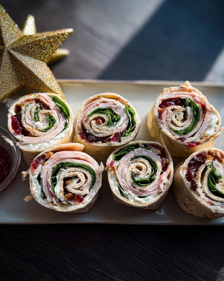 Six slices of Christmas Cranberry Turkey Roll Ups arranged on a platter next to a golden star decoration.