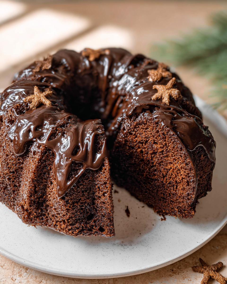 A delicious Gingerbread Chocolate Bundt Cake with a slice cut out, drizzled with chocolate ganache and decorated with gingerbread stars.