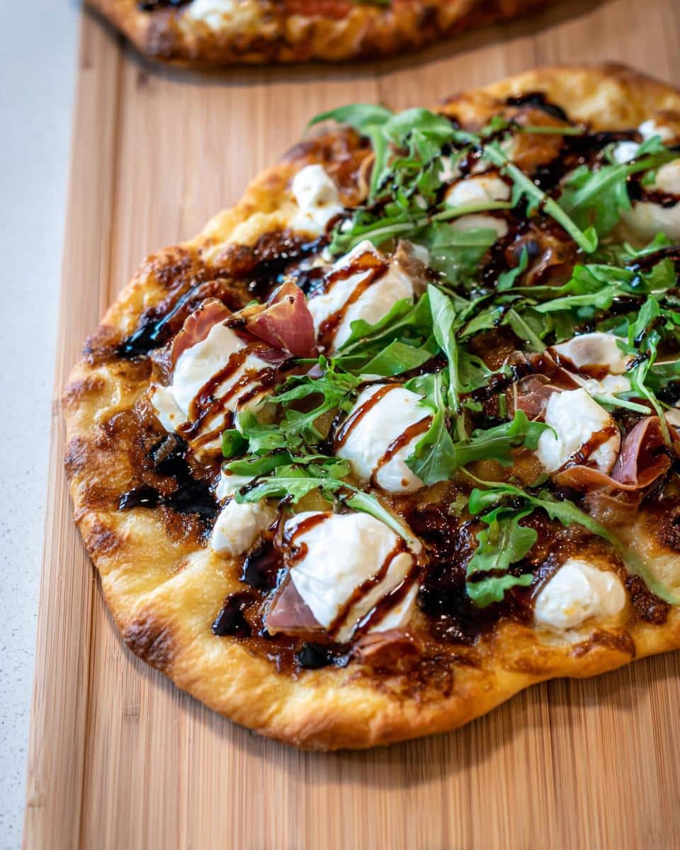 Close-up of a finished 5-Ingredient Flatbread Pizza topped with fresh mozzarella, prosciutto, arugula, and balsamic glaze.