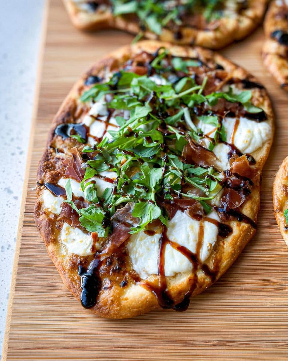 Close-up of a finished 5-Ingredient Flatbread Pizza topped with fresh mozzarella, prosciutto, arugula, and balsamic glaze.
