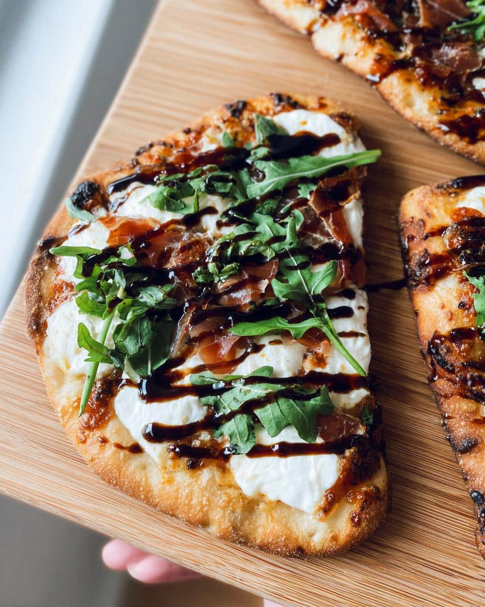 A slice of 5-Ingredient Flatbread Pizza topped with fresh mozzarella, prosciutto, arugula, and balsamic glaze.
