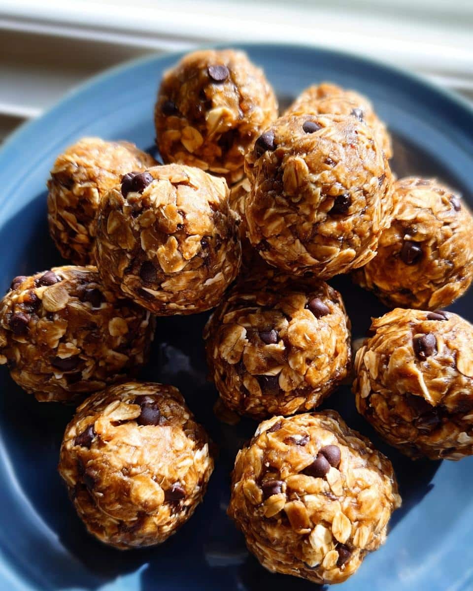 A pile of homemade no-bake protein ball treats studded with visible oats and mini chocolate chips, served on a blue plate.