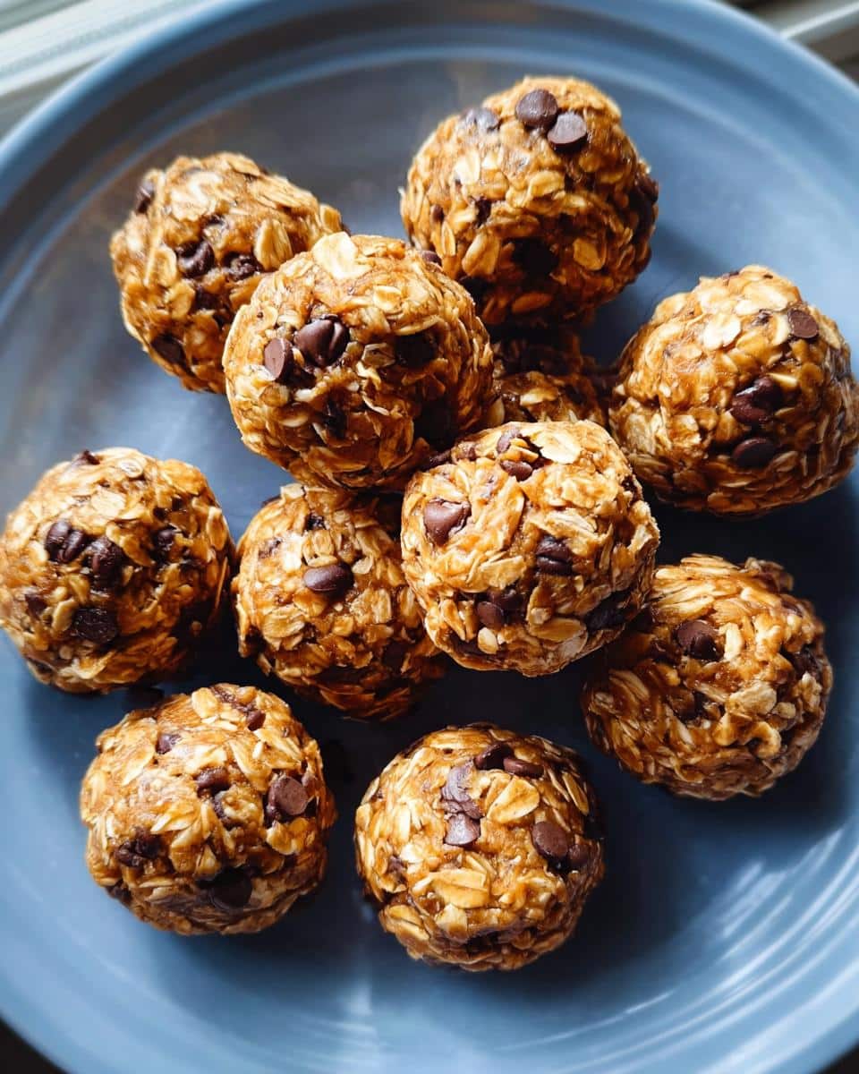 A pile of chocolate chip no-bake protein ball treats made with oats, resting on a blue plate.