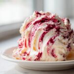 A close-up of the creamy Cranberry Orange Holiday Dip, showing rich swirls of white cream cheese base and deep red cranberry sauce.