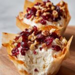 Two Cranberry Pecan Cream Cheese Mini Cups in flaky phyllo shells, topped with dried cranberries and pecans.