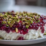 Close-up of the amazing Cranberry Pistachio Cold Cream Cheese Dip topped with bright red cranberry sauce and chopped green pistachios.