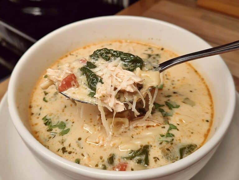 A spoonful of creamy Crockpot Marry Me Chicken Soup showing shredded chicken, spinach, and parmesan cheese.