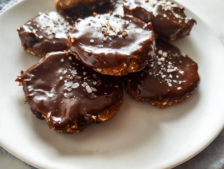 A stack of rich Date & Cocoa No-Bake Cookies topped with glossy chocolate glaze and flaky sea salt.