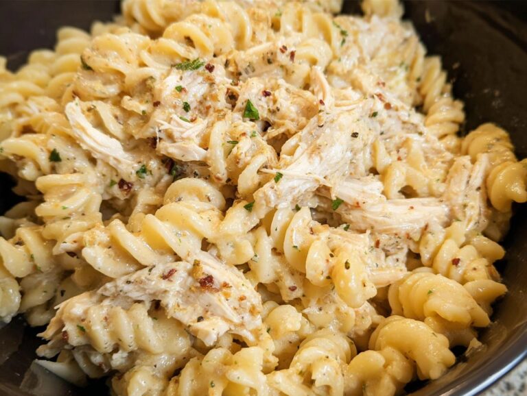 Close-up shot of creamy Easy Crockpot Garlic Parm Chicken Pasta made with rotini noodles and shredded chicken.