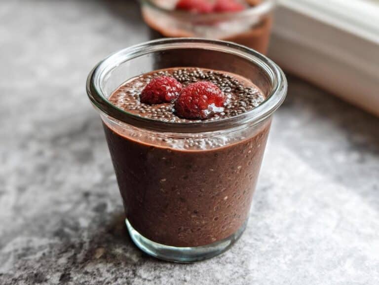 Close-up of Easy Keto Chocolate Chia Seed Pudding topped with two fresh raspberries.