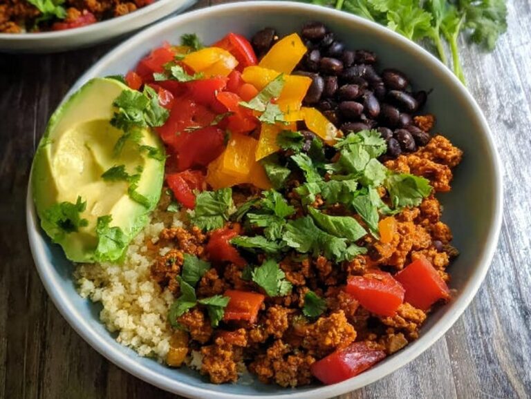 Close-up of a vibrant Healthy Taco Bowl featuring seasoned ground meat, black beans, avocado, peppers, and cilantro.