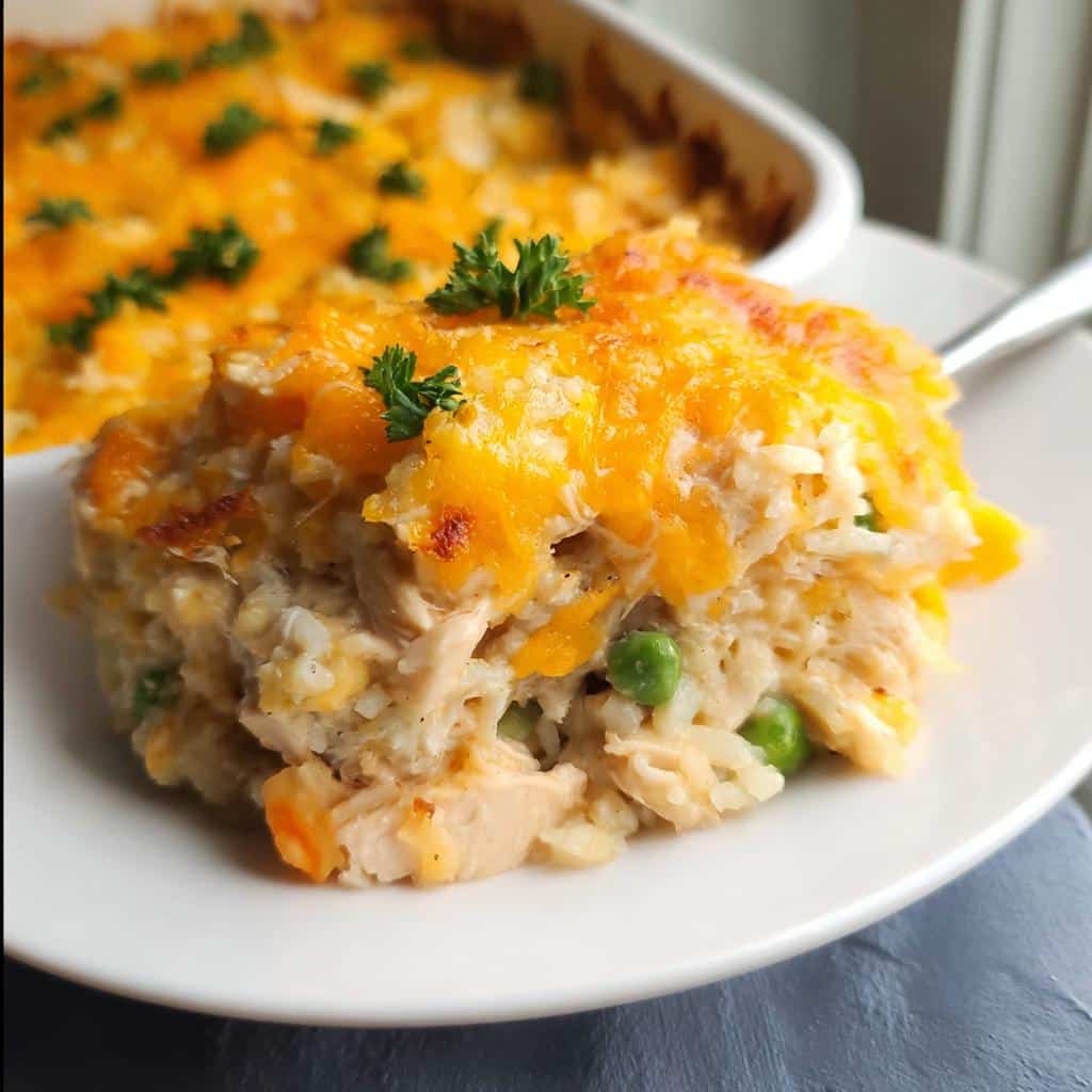 A scoop of creamy Gluten-Free Chicken and Rice Casserole topped with melted cheddar cheese and parsley.