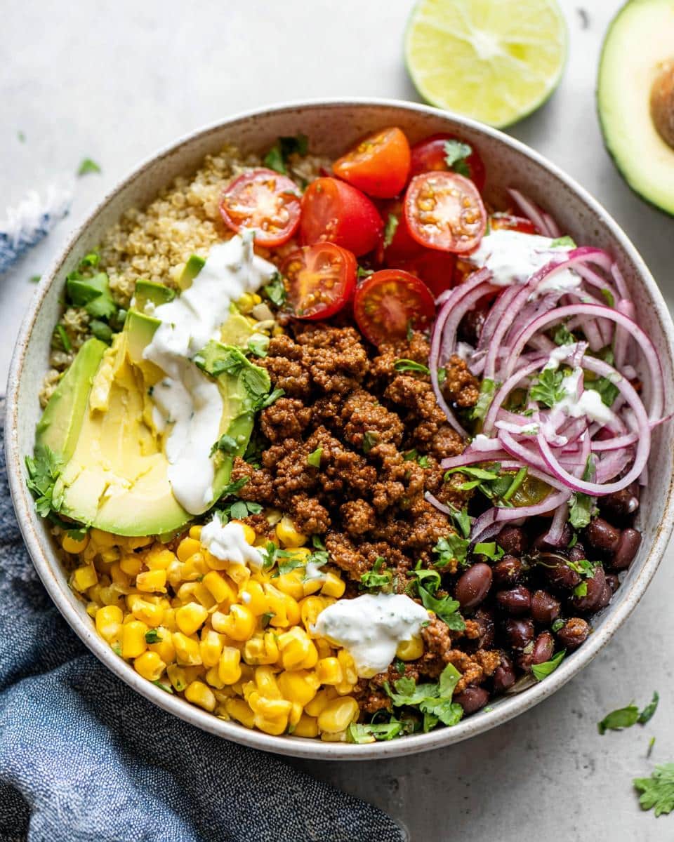 Overhead view of a vibrant Healthy Taco Lunch Bowl featuring seasoned ground meat, quinoa, black beans, avocado, and red onion.