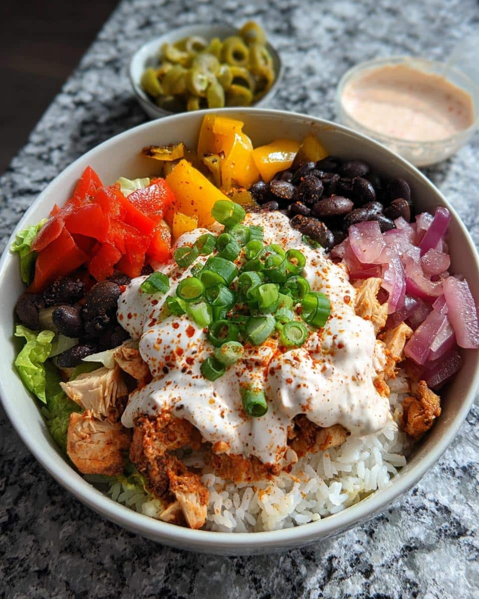 A vibrant High-Protein Chicken Rice Bowl featuring seasoned chicken, white rice, black beans, peppers, and creamy sauce.
