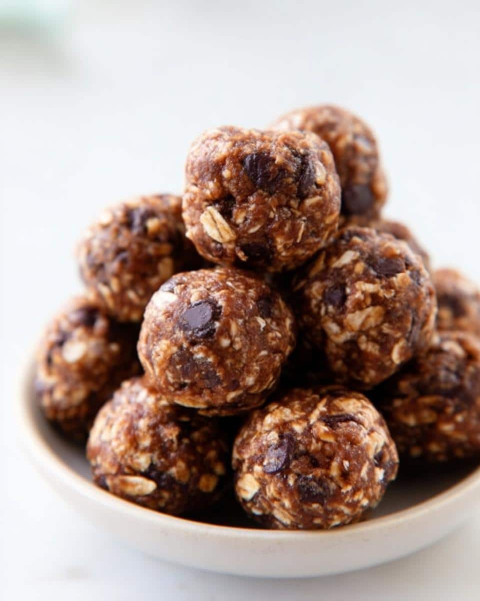 A close-up stack of homemade Peanut Butter Chocolate Energy Bites mixed with visible oats and chocolate chips.