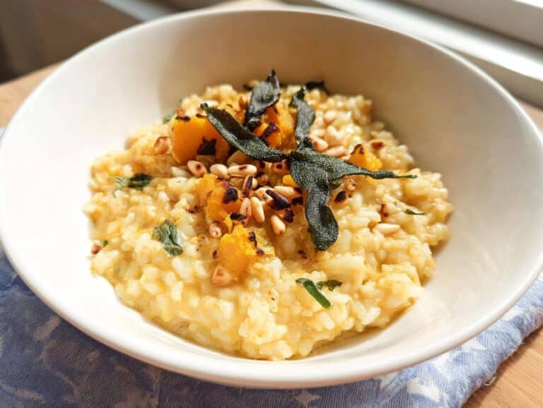 A close-up view of creamy Pumpkin & Sage Thermomix Risotto topped with roasted pumpkin, pine nuts, and crispy sage leaves.