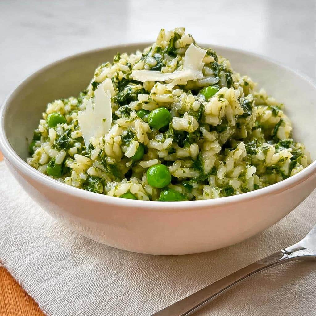 A creamy bowl of Risotto with Spinach and Peas- Thermomix, topped with shaved Parmesan cheese.
