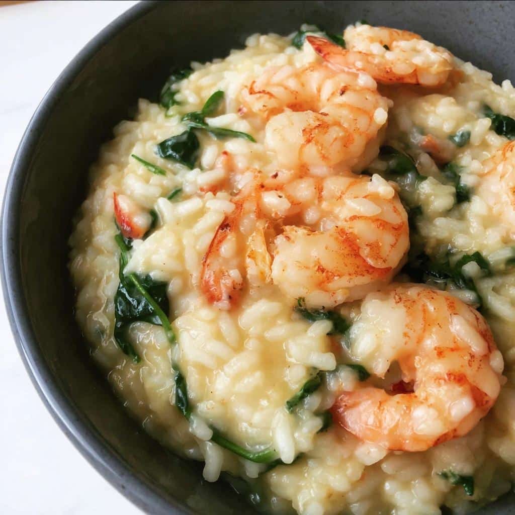 Close-up of creamy Thermomix Garlic Prawn Risotto topped with perfectly cooked prawns and wilted spinach.