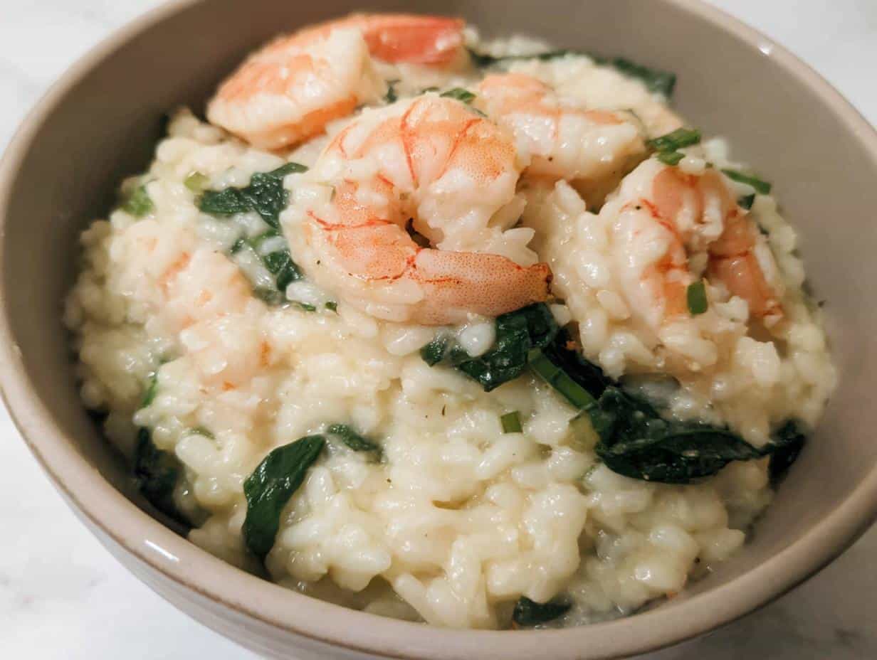 Close-up of creamy Thermomix Garlic Prawn Risotto topped with pink shrimp and wilted spinach.