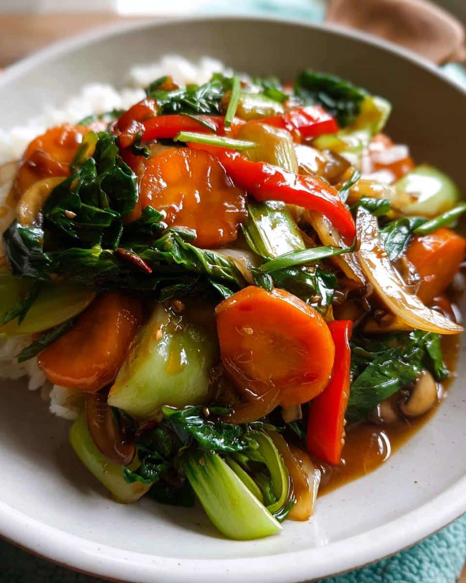 A close-up of Vegetable Stir Fry with Light Sauce featuring carrots, bok choy, and red peppers served over white rice.