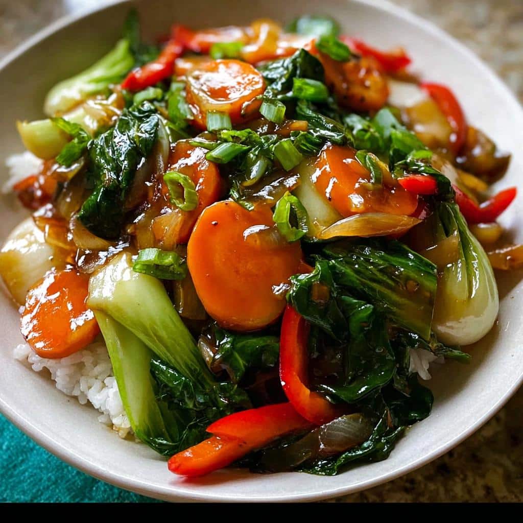 Close-up of a vibrant Vegetable Stir Fry with Light Sauce featuring bok choy, carrots, and red peppers over white rice.