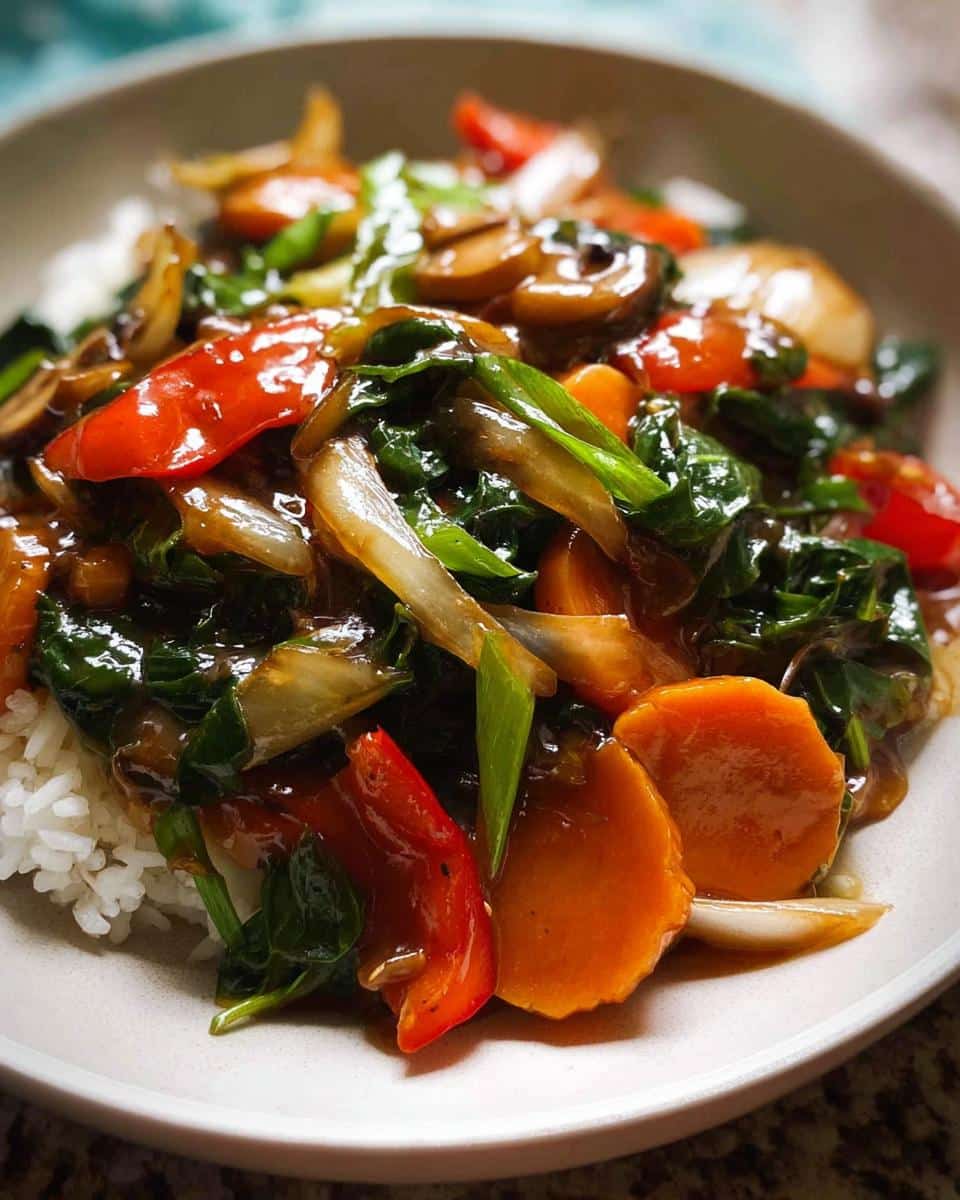 A close-up of a savory Vegetable Stir Fry with Light Sauce featuring carrots, red peppers, spinach, and mushrooms served over white rice.
