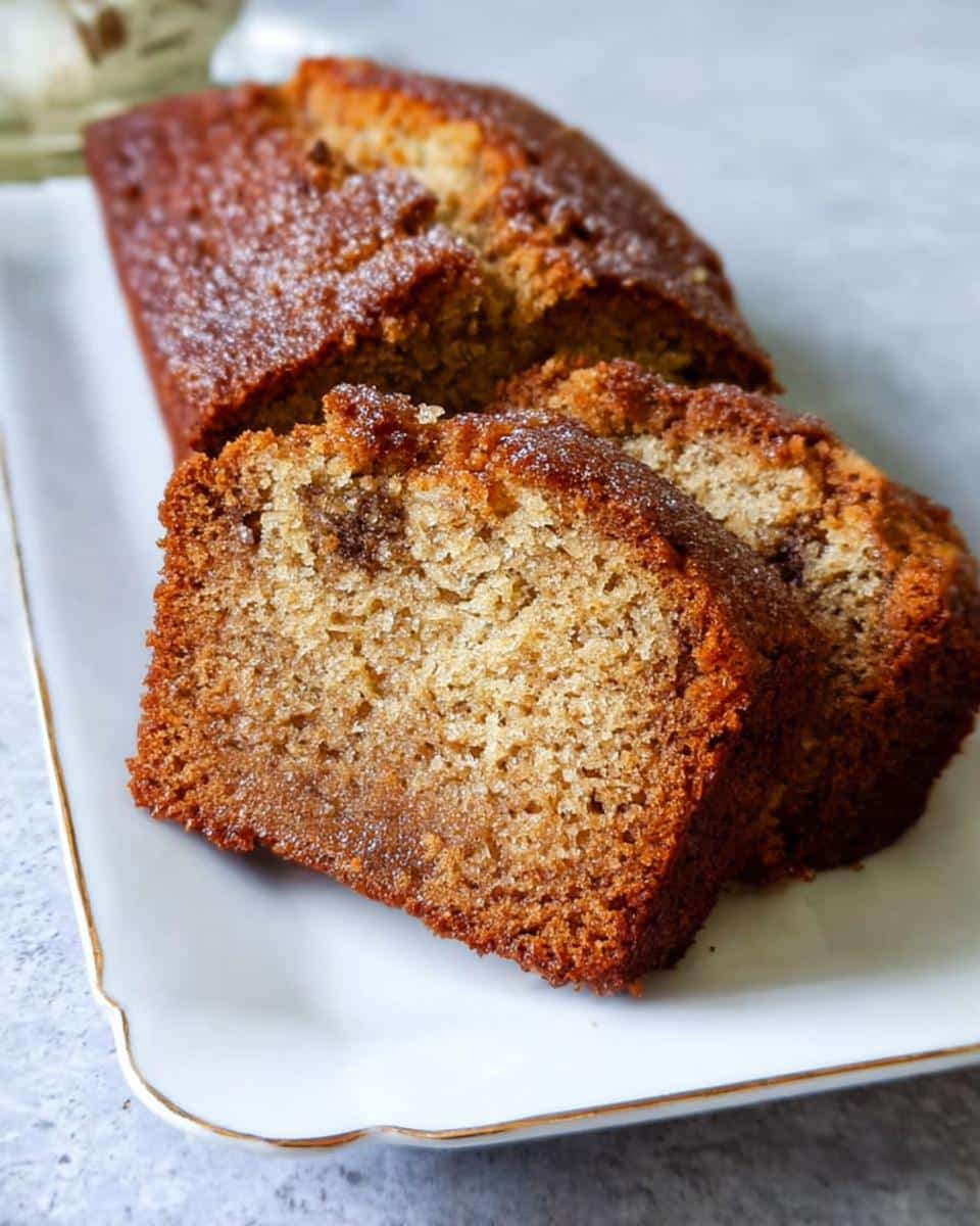 Close-up of moist Banana Bread Air Fryer, sliced and served on a white plate with gold trim.