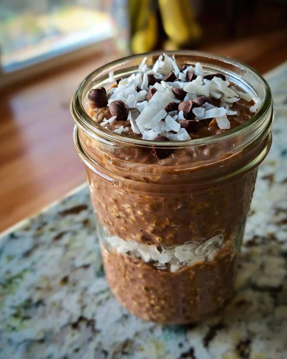 Close-up of Chocolate Coconut Overnight Oats layered with coconut flakes in a glass jar.