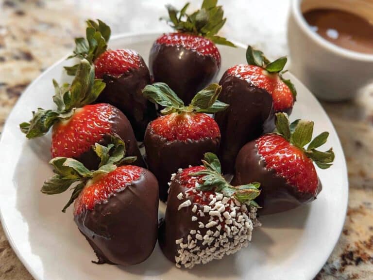 A plate of freshly made Chocolate Covered Strawberries, some plain and one with white sprinkles.