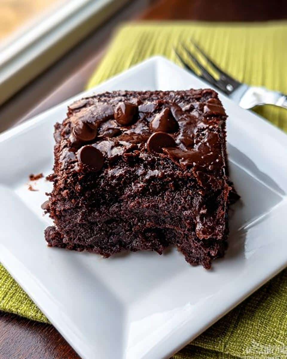 A rich, moist slice of Chocolate Pudding Dump Cake topped with melted chocolate and chips.