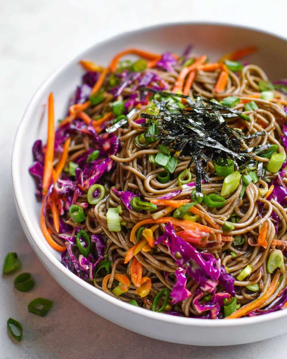 Close-up of a Cold Soba Noodle Lunch Bowl topped with shredded purple cabbage, carrots, and nori.