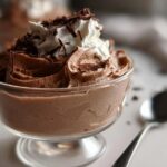 A close-up of rich Gluten Free Chocolate Mousse served in a glass dish, topped with whipped cream and chocolate shavings.