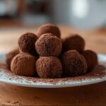 A mound of rich Gluten Free Chocolate Truffles dusted heavily with cocoa powder, served on a white plate.