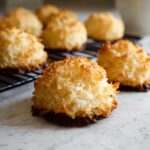 Close-up of golden brown Gluten Free Coconut Macaroons dipped in dark chocolate, cooling on a rack.