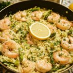Close-up of Gluten Free Lemon Orzo with Shrimp and asparagus, garnished with a lemon slice.