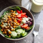 Overhead view of a Gluten Free Mediterranean Chickpea Bowl featuring roasted chickpeas, quinoa, tomatoes, cucumber, and a green dressing.
