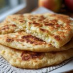 A stack of three golden-brown Gluten Free Protein Flatbread Wraps, one cut open to show the filling.