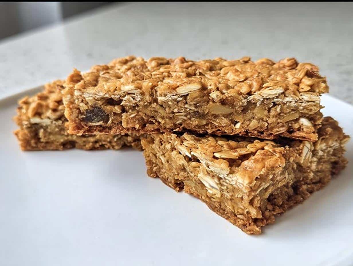 Two stacked Gluten-Free Savory Oat Bars showing texture of oats, nuts, and dried fruit on a white plate.