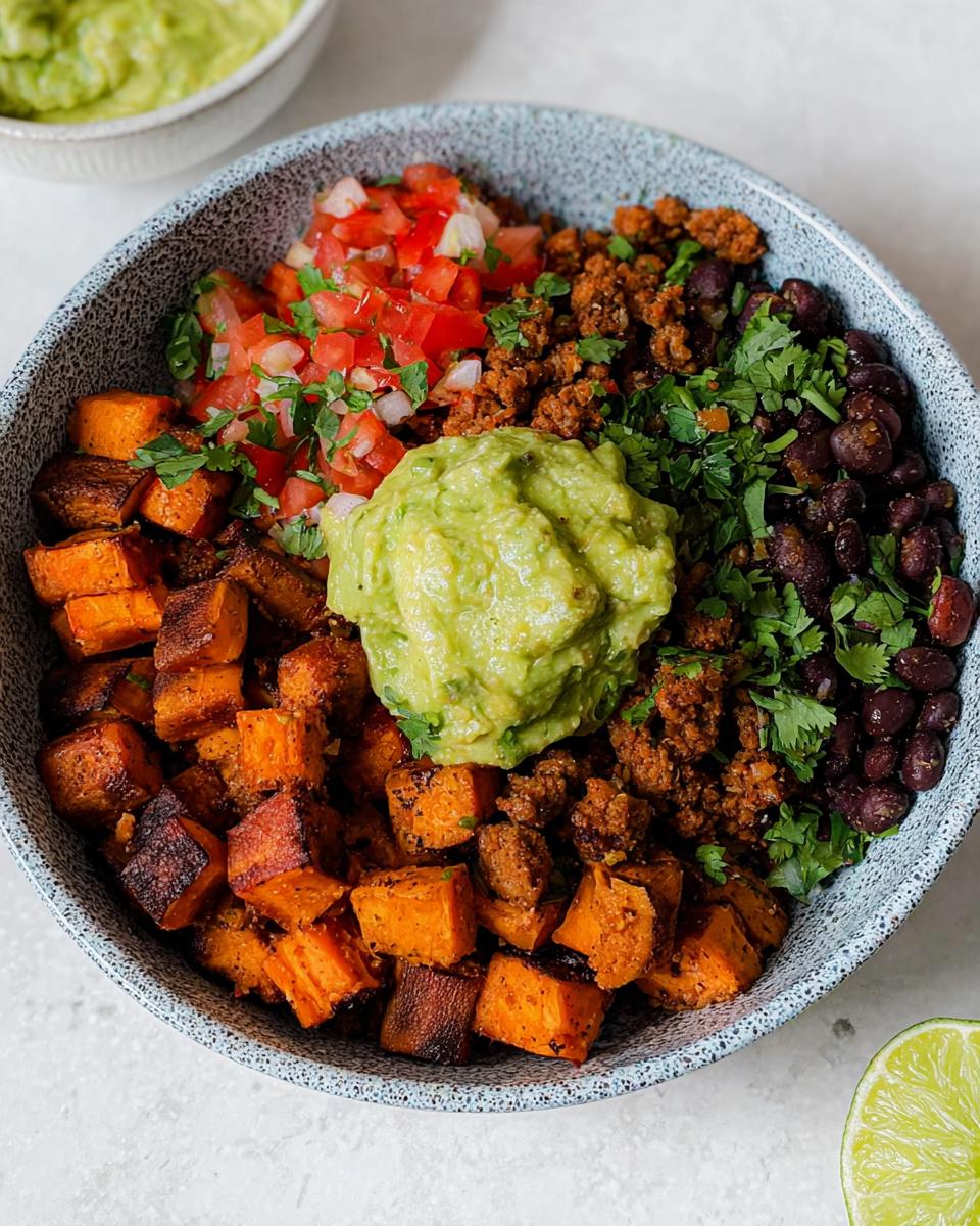 Close-up of Gluten Free Sweet Potato Taco Bowls featuring roasted sweet potatoes, black beans, taco meat, pico de gallo, and guacamole.