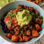 A vibrant bowl of Gluten Free Sweet Potato Taco Bowls topped with seasoned meat, black beans, pico de gallo, and a dollop of guacamole.