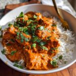 Close-up of a white bowl filled with Gluten Free Tikka Masala Bowls, featuring rich orange curry over white rice, topped with fresh cilantro.